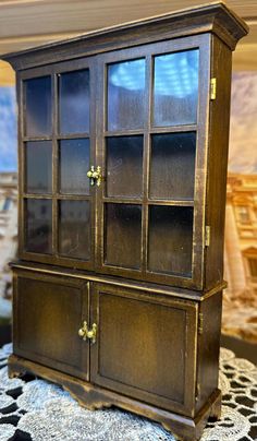 an old wooden china cabinet with glass doors on the top and bottom shelves, sitting on a table