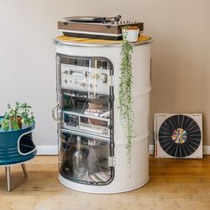 an old record player sitting on top of a tall white container with plants growing out of it