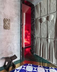 an artisticly designed bathroom with colorful tiles and floor to ceiling wall panels, along with a black chair