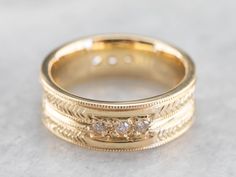 This engraved band is of a perfect heft and shape to feel soft and pleasant on the finger. It is both pretty and sophisticated, and it would be a great wedding or stacking band for a woman who wants a little extra sparkle but works with her hands. Metal: 18K Yellow Gold Gem: 12 Diamonds totaling .36 Carats, F in Color, VVS in Clarity Width of Band: 6.5 mm Height off Finger: 1.9 mm Ring Size: 6 Marks: "AA18K" Stamped on the inside band Fine Jewelry Wedding Rings With Milgrain Detail, Fine Jewelry Engraved Ring With Decorative Band, Luxury Engraved Promise Ring With Decorative Band, Luxury Stackable Rings With Thick Band For Wedding, Wedding Ring With Single Cut Diamonds And Thick Band, 14k Gold Bands With Diamond Accents, Yellow Gold Diamond Jewelry With Milgrain Detail, Gold Diamond Rings With Milgrain Detail, Luxury Diamond Cut Promise Band