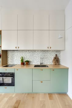 a kitchen with white cabinets and light wood flooring, including an oven and dishwasher