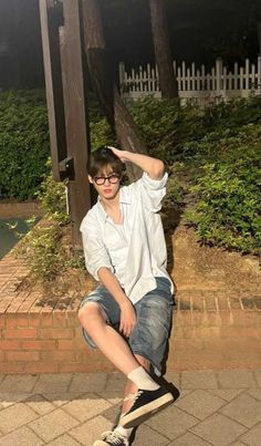 a young man sitting on top of a wooden pole