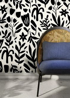 a blue chair sitting in front of a wall with black and white designs on it