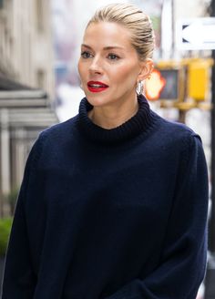 a woman with red lipstick is walking down the street