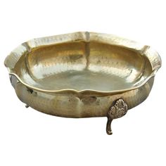 a metal tray with an ornate design on the bottom and foot rests in front of a white background