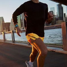 a man running across a bridge near the water with buildings in the backgroud