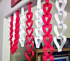 paper hearts hanging from the ceiling in front of a computer desk with a monitor on it