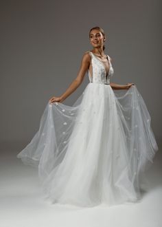 a woman in a white wedding dress posing for the camera with her veil draped over her shoulders