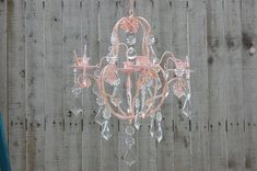 a pink chandelier hanging from a wooden fence