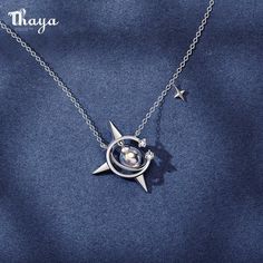 a silver necklace with a star and moon in the center on a blue background that says thaya