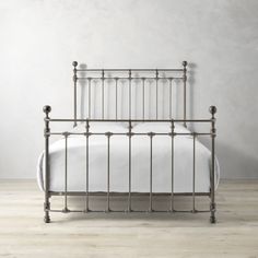 an iron bed frame with white sheets and pillows