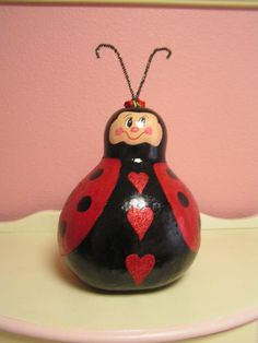 a lady bug figurine sitting on top of a white table next to a pink wall