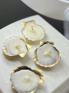 three scallop shells sitting on top of a white box with gold flecks