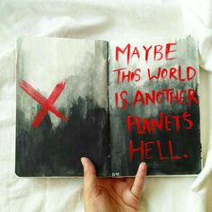 a hand holding an open book with red writing on it and the words maybe this world is another planet hell