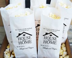 four bags of popcorn sitting on top of a wooden box filled with white paper bags