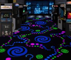 an interactive video game room with neon colored carpeting and arcade machines in the background