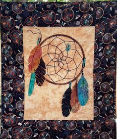 a wall hanging with a dream catcher on it's side and feathers in the center