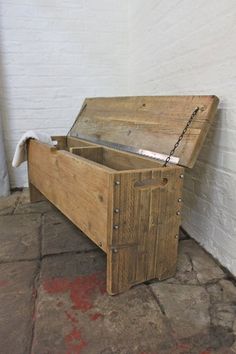 an old wooden chest sitting on top of a stone floor next to a white brick wall