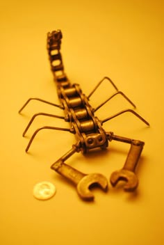 a small metal insect sitting on top of a table next to a coin and screwdriver