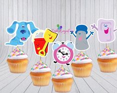 cupcakes with frosting and cartoon characters on them are arranged in a row