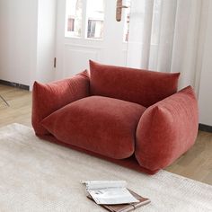 a red couch sitting on top of a white rug