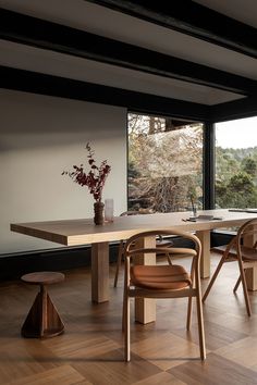 a dining room table and chairs in front of large windows