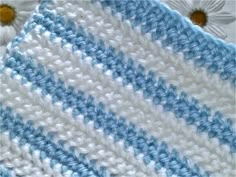 a crocheted blue and white blanket sitting on top of a flowered table