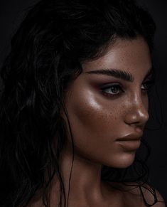 a woman with freckles on her face and dark hair is posing for the camera