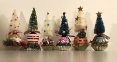 a row of christmas trees sitting next to each other on top of a white table