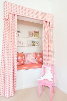 a pink and white canopy bed in a girls's bedroom with pillows on it