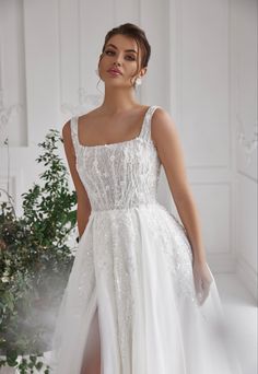 a woman in a white wedding dress standing next to a plant