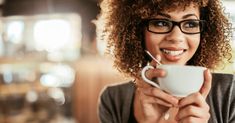 a woman with glasses holding a cup and smiling