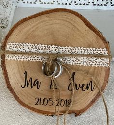 a wooden slice with two wedding rings tied to it and the date written on it