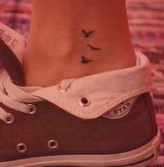 a close up of a person's foot with a bird tattoo on their ankle