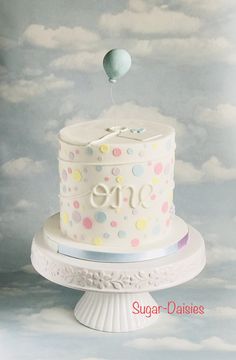 a white cake with polka dots on it and a balloon in the sky above it