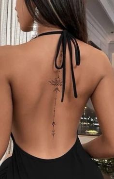 the back of a woman wearing a black dress with an arrow tattoo on her lower back