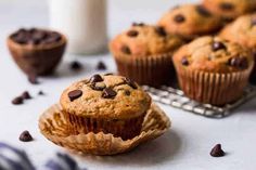 chocolate chip muffins sitting on a cooling rack next to a glass of milk