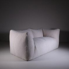 a white couch sitting in the middle of a room with no one on it's legs