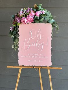 a pink sign with flowers on it that says oh baby welcome to masha's baby shower