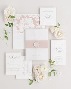 the wedding stationery is laid out on top of each other with flowers and greenery