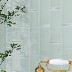 a bathroom sink with a gold faucet next to it and a potted plant in the corner