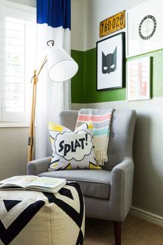 a gray chair sitting in front of a window next to a lamp and pictures on the wall