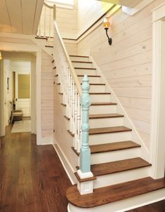 the stairs in this house are made of wood and have white railings with blue balconies