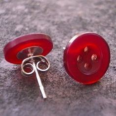 two red buttons sitting next to each other on top of a stone surface with one button missing