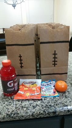 two brown bags sitting on top of a counter next to an orange and some snacks