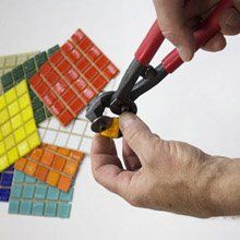 a man is using scissors to cut colored tiles