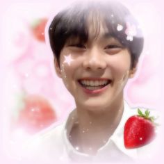 a young man smiling and holding a strawberry