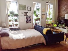 a bed sitting in the middle of a bedroom next to two windows with potted plants on them