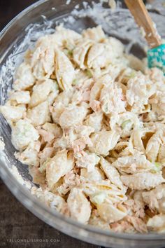 a bowl full of chicken salad with a wooden spoon