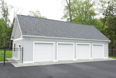 a white garage with two doors and a black gate